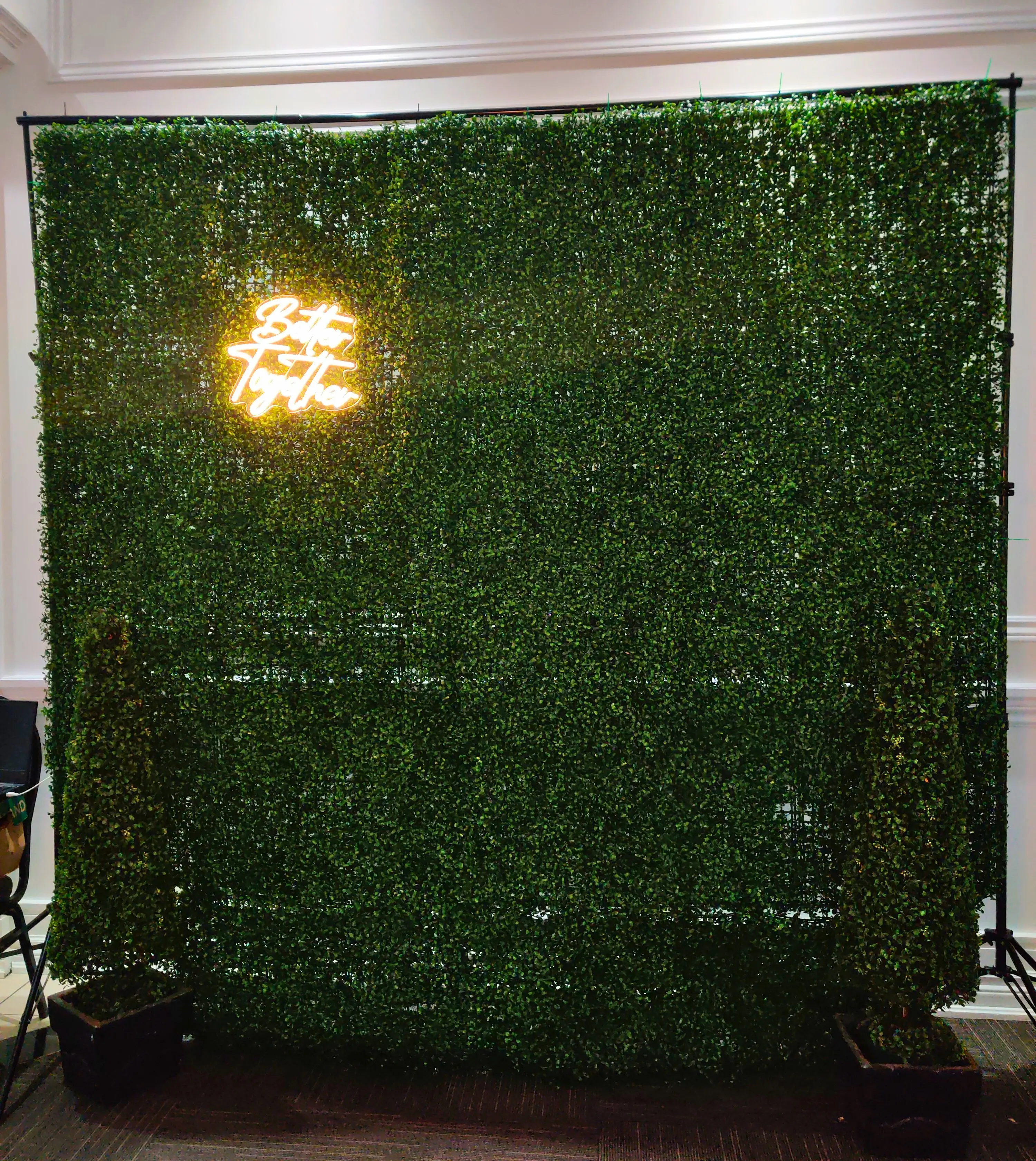 Lush greenery wall with a neon sign saying 'Better Together', set up as a photobooth backdrop for weddings or special events, adding a touch of nature-inspired elegance provided by Rent a PhotoBooth photobooth rentals.