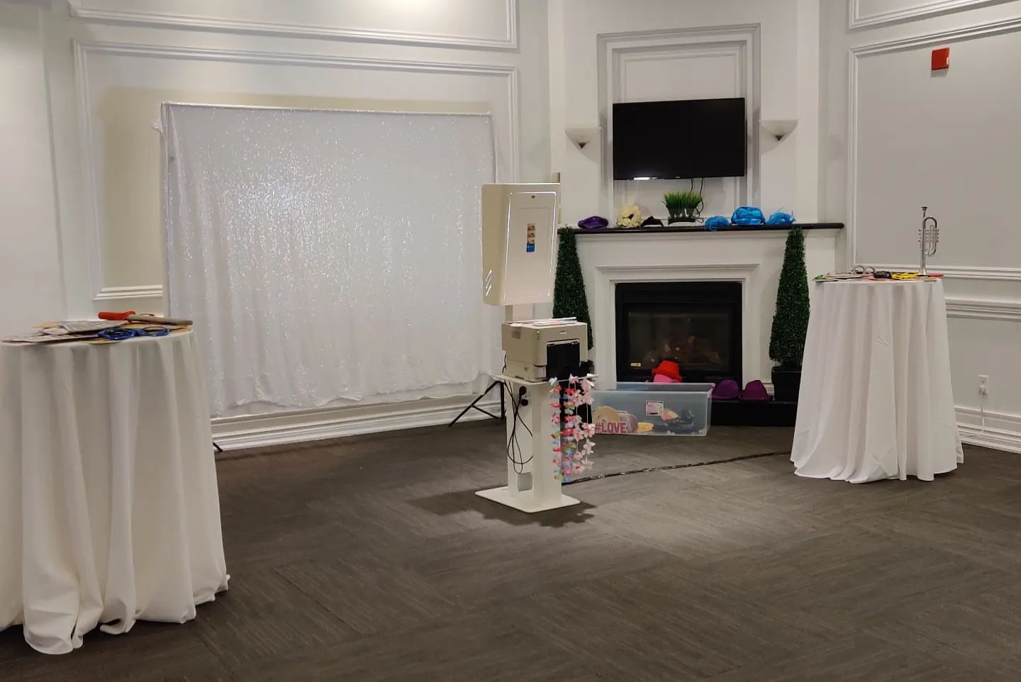 Photobooth setup at an elegant indoor venue with a white sparkling backdrop, prop table, and photobooth equipment including a kiosk and printer, ready for guests to capture fun moments, provided by Rent a PhotoBooth photobooth rentals.